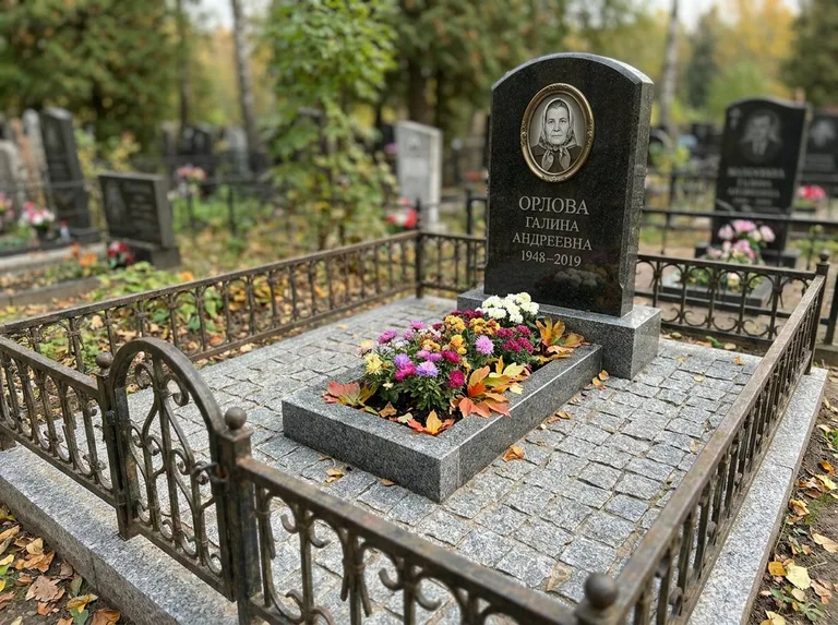 Благоустроенное захоронение с гранитной плиткой, оградой и цветником в Омске
