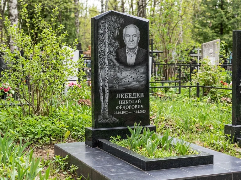 Памятник с гравировкой берёзы: вертикальная стела со скошенным верхом — берёза и стая птиц в небе, гранитный цоколь с тёмной плиткой, работа «Лебедев» в Омске