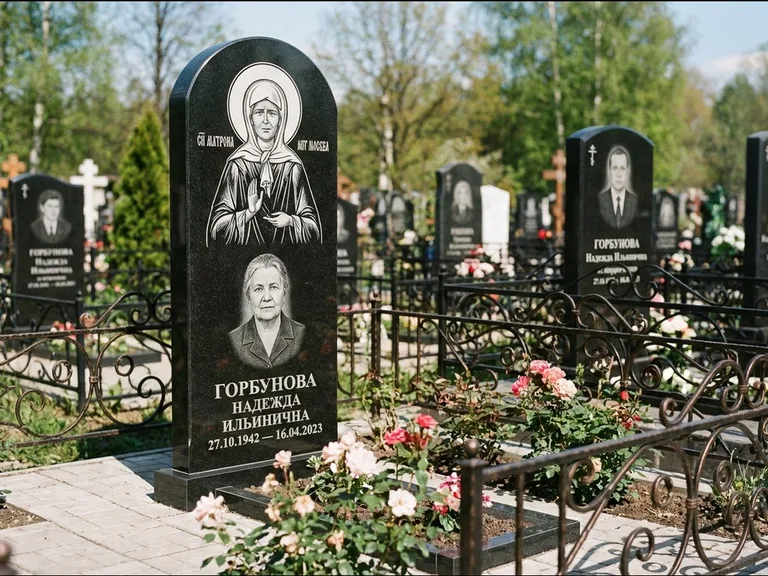 Памятник с гравировкой иконы: стела с арочным верхом и киотом под образ — гравировка образа Матроны Московской, гранитный цоколь с тёмной плиткой, работа «Ковалёв» в Омске