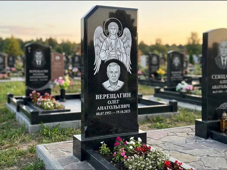 Памятник с гравировкой иконы: стела с резным навершием и нимбом в золоте — гравировка образа Спасителя, высокие разросшиеся туи полукругом, работа «Мельникова» в Омске