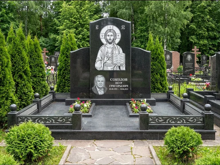 Памятник с гравировкой иконы: широкая горизонтальная лежачая плита-стела — икона в резной рамке-киоте, серая гравийная отсыпка с бордюром, работа «Богданова» в Омске