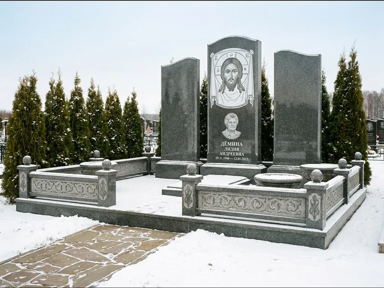 Памятник с гравировкой иконы: узкая вертикальная стела-пилон с ликом — икона в резной рамке-киоте, открытая лужайка без ограды, работа «Одинцов» в Омске