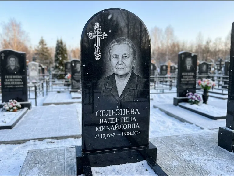 Памятник из чёрного гранита — массивная стела с крестом в лучах с крестом в лучах, работа «Одинцова» в Омске
