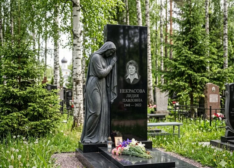 Гранитная фигура скорбящего мужчины у чёрной стелы в Омске