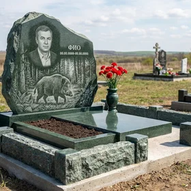 Гранитный памятник охотнику с фактурой скалы с лесной чащей